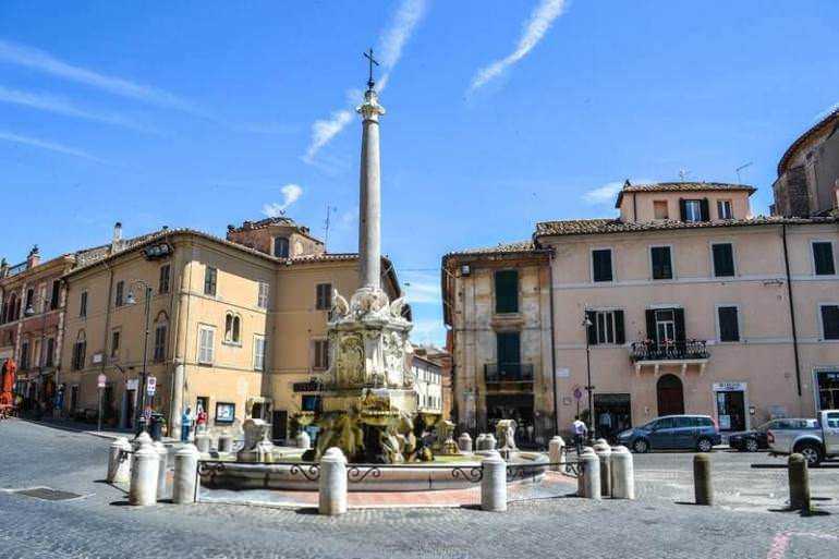 Tarquinia e necropoli etrusche: Necropoli etrusca di monterozzi: Franchettina antica al centro di una piazza storica con edifici tradizionali e cielo azzurro, luogo di interesse culturale e turistico