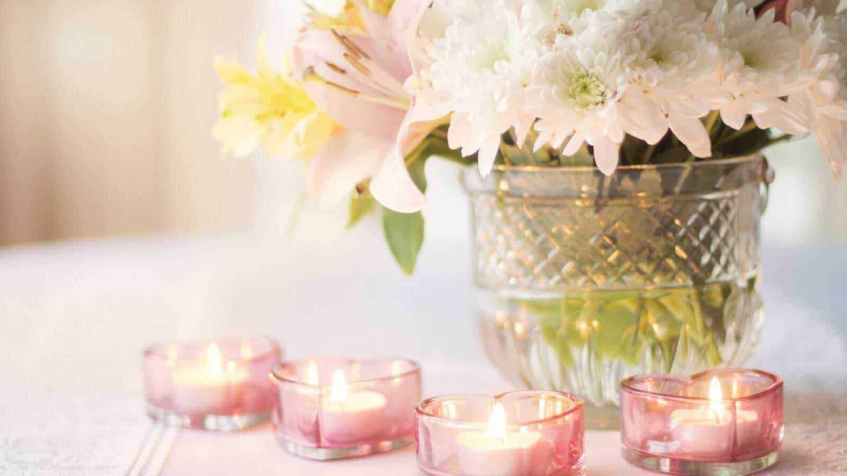 Fiori decorativi in vaso con candele rosa accese, ambiente elegante e romantico.