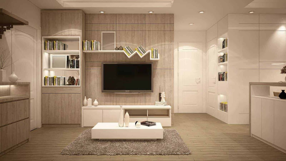 Design moderno di soggiorno con pareti chiare, scaffali con libri e TV, arredamento minimale, tappeto morbido e decorazioni eleganti, ambiente accogliente e raffinato.
