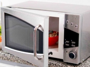 Microonde in camera da cucina con porta aperta, stoviglie e verdure fresche sul piano di lavoro, Lifestyle domestico, apparecchiature da cucina moderne, preparazione pasti.