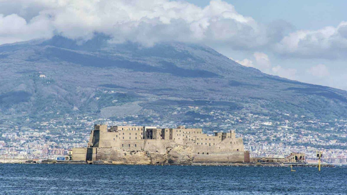 Castello di Ischia vista dal mare con il vulcano sullo sfondo, panorama storico e naturale dell'isola di Ischia in Italia.