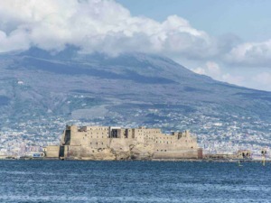 Castello di Ischia vista dal mare con il vulcano sullo sfondo, panorama storico e naturale dell'isola di Ischia in Italia.