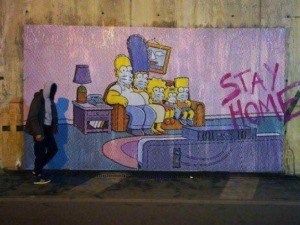 Famiglia Simpson dipinta su un muro con scritta Stay Home, immagine di arte urbana e street art, rappresenta cultura pop e il tema del lockdown e isolamento domestico.