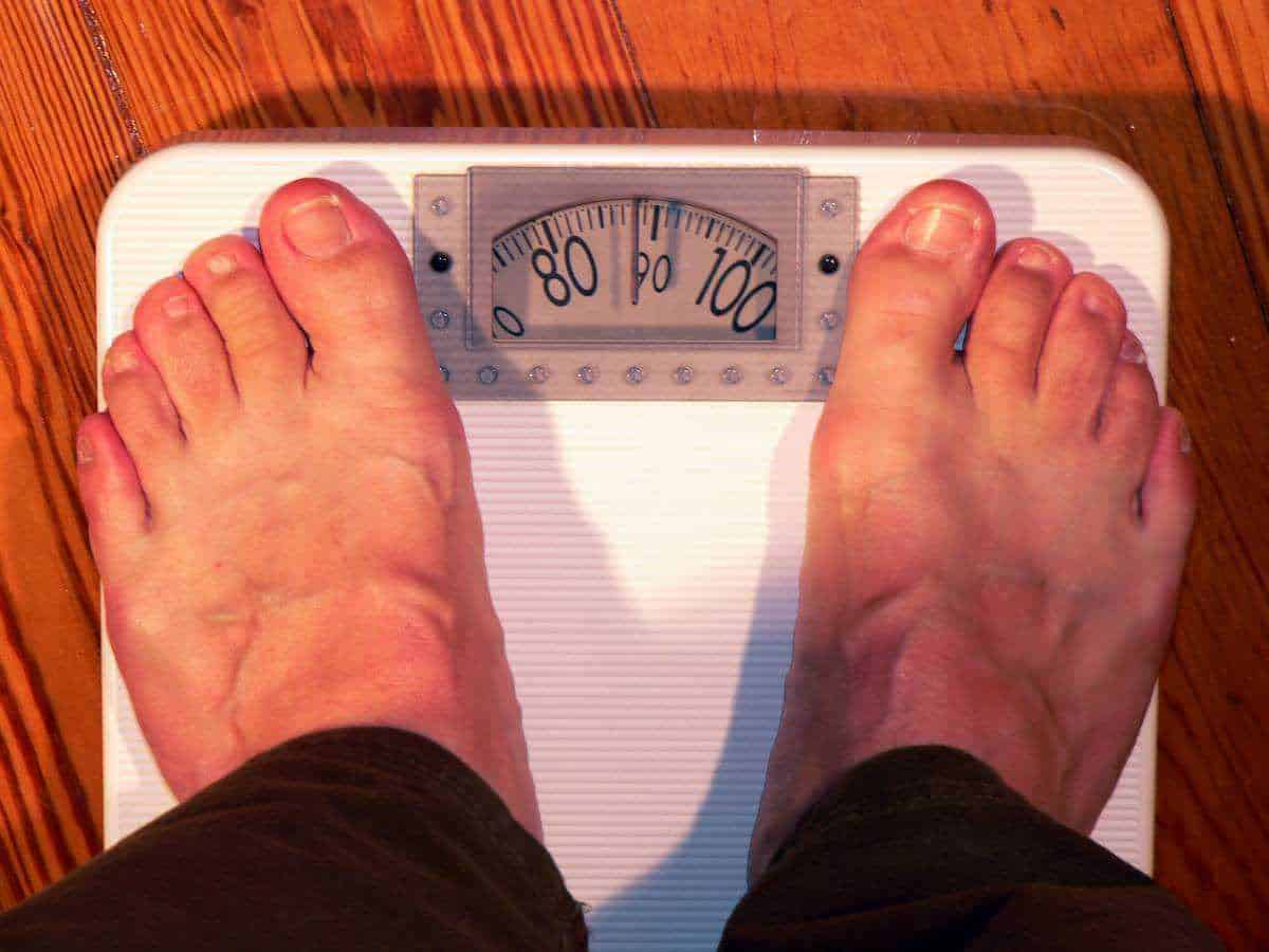 Malattie che causano l'obesità: Bilancia digitale per pesare i piedi di una persona, focus su benessere e controllo peso.