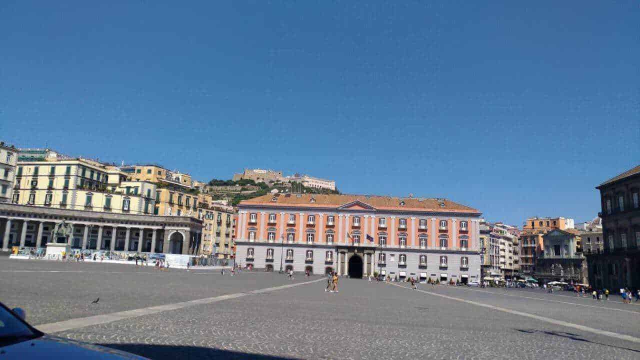Palazzi neoclassici e ville liberty a napoli: Tradizionale piazza centrale con edifici storici e vista sul castello in alto in Napoli, Italia. Luogo emblematico ricco di storia e cultura, ideale per passeggiate e scoprire il patrimonio cittadino.