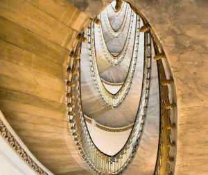 Elegante scena di un edificio con scale interne a spirale in legno e illuminazione calda, atmosfera moderna e sofisticata, dettagli architettonici di alta qualità.