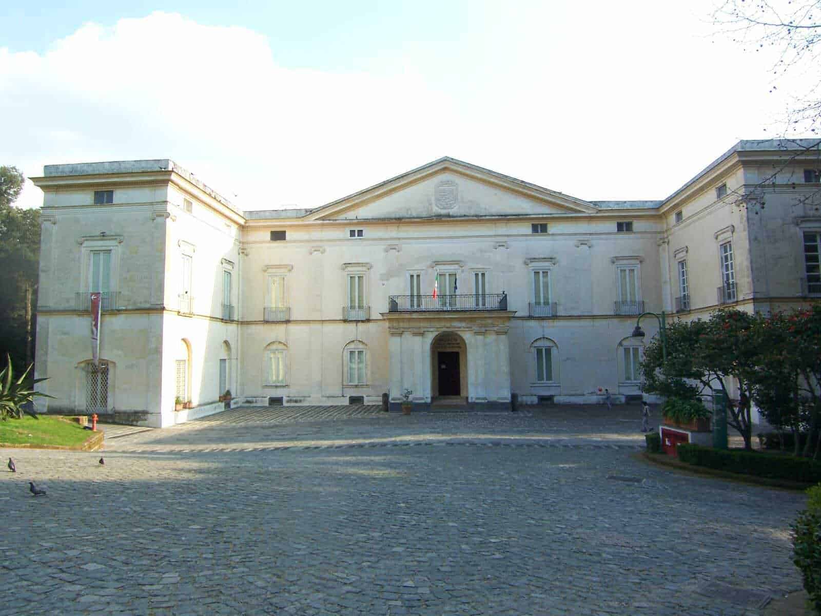 Villa storica in stile neoclassico con facciata bianca e dettagli architettonici eleganti, immersa in un giardino curato, rappresenta un esempio di architettura storica italiana.