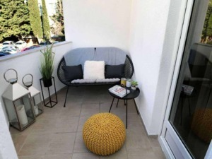 Accogliente balcone con seduta moderna e cummerse di cuscini neri e bianca, arredi eleganti con piante e candela, ideale per relax e momenti di relax all'aperto.