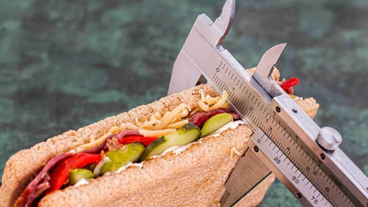 Sandwich integrale con verdure e affettati, misura con calibro, concetto di abbigliamento e cibo, immagine di cibo salutare e nutriente.