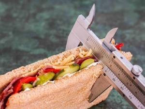 Sandwich integrale con verdure e affettati, misura con calibro, concetto di abbigliamento e cibo, immagine di cibo salutare e nutriente.