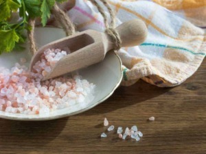 Sale rosa grosso per cucina integrata in sale naturale, ideale per arricchire piatti e alimenti, con cucchiaio di legno su piatto di ceramica, sul tavolo di legno.