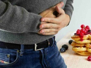 Mal di stomaco da cibo o digestione, persona dolorante con stomaco che si stringe, pancake con marmellata e frutti di bosco, problema digestivo.