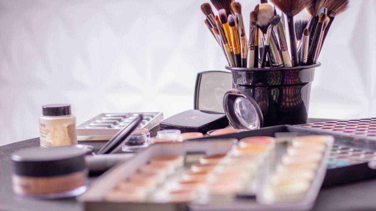 Pennelli e prodotti per il trucco disposti su un tavolo, ideale per tutorial di makeup e beauty blog. Strumenti professionali per il makeup artist, ambientazione di un set di trucco.