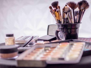 Pennelli e prodotti per il trucco disposti su un tavolo, ideale per tutorial di makeup e beauty blog. Strumenti professionali per il makeup artist, ambientazione di un set di trucco.