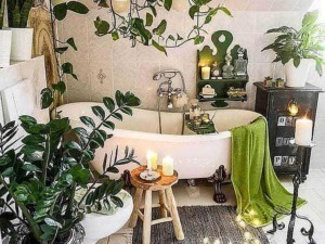 Fioritura di piante verdi in bagno con vasca da bagno vintage, illuminata da candele e luci soffuse, creando un'atmosfera rilassante e naturale.