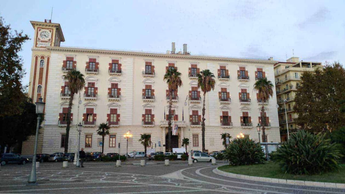 Appunti Sul Blog building con facciata storica e palme, centro città Sicilia, architettura urbana e turismo locale, immagini di carattere storico e culturale.