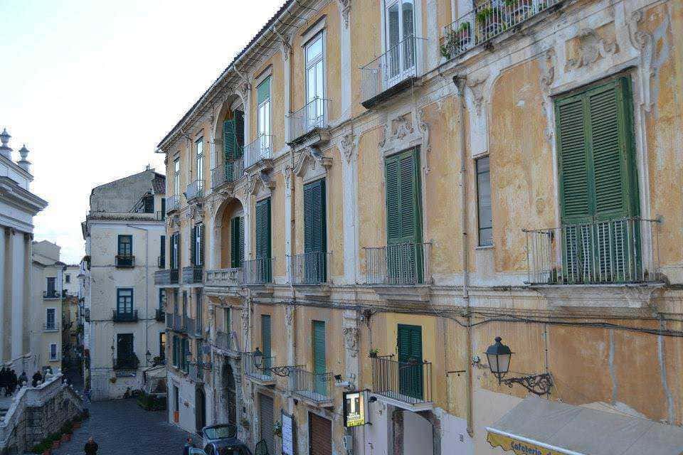 Vecchie facciate di edifici storici a città italiana, edifici con balconi e persiane verdi, immagine di architettura urbana in Italia, edificio con pareti dipinte di giallo, veduta di strada cittadina, immagini di architettura italiana, immagine storica di quartiere italiano, strada urbana con edifici storici