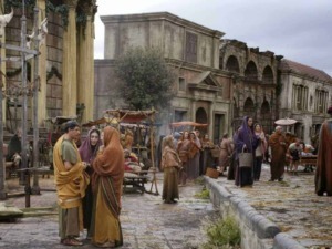 Antico mercato romano ricostruito con attori in costumi dell'epoca, scena storica e ambientazione archeologica, rappresentazione di vita quotidiana nell'antica Roma.