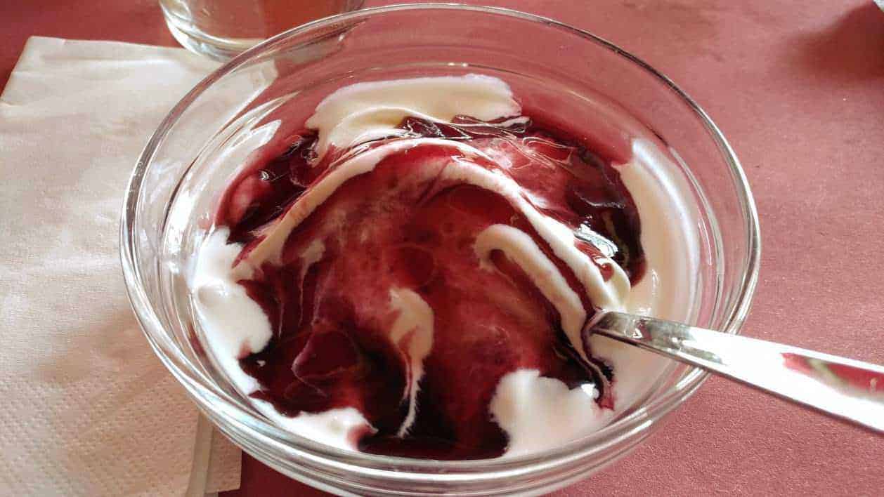 Gelato, merenda estiva. Quali gusti meno calorici scegliere? 5 Crema di yogurt e frutti di bosco in una ciotola trasparente, perfetta per dessert estivi genuini e salutari.