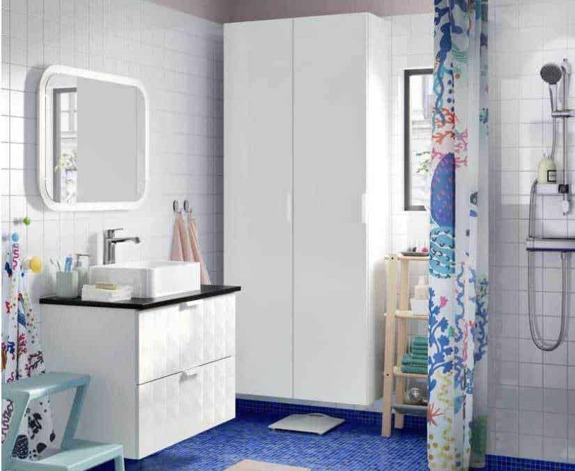 Armadio bagno bianco con tubo doccia e tende colorate, area lavabo con specchio illuminato, mobili e accessori per il benessere e l’igiene in bagno, decorazione originale e funzionale della stanza.