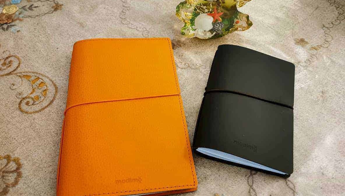 Highlighted notebooks and decorative shell on elegant tablecloth.