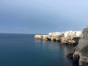 Pensilina sulla scogliera con case bianche sul mare, viste dal mare, coste di roccia e acque turchesi, paesaggio costiero mediterraneo, promotes Italy travel, turismo costiero e bellezze naturali.