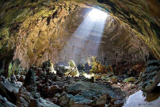 Viaggio in Puglia con Voyage Privé: 7 luoghi più belli da visitare 3 Caverna naturale con luce solare che entra dal soffitto, rocce e terra nel interno di una grotta, paesaggio sotterraneo suggestivo e misterioso.