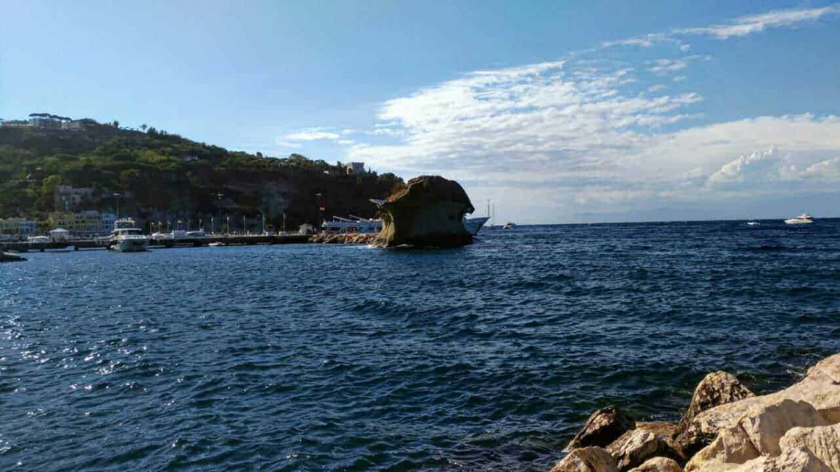 Scogliera e mare a Capri con yacht e barche, paesaggio marino italiano.