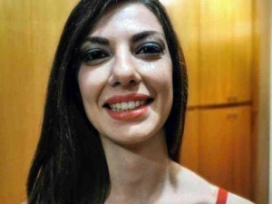 Bellissima donna sorridente con trucco intenso e capelli lunghi, sfondo di mobili in legno, ideale per articoli su bellezza, stile e lifestyle femminile.