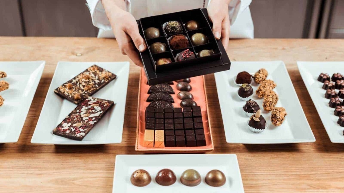 Deliziosi cioccolatini artigianali e dolci assortiti su piatti raffinati, perfetti per cioccolato e dessert di qualità, presentati su un tavolo di legno.