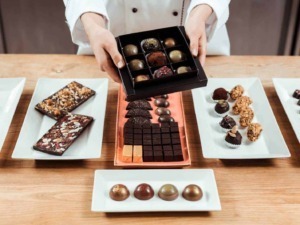Deliziosi cioccolatini artigianali e dolci assortiti su piatti raffinati, perfetti per cioccolato e dessert di qualità, presentati su un tavolo di legno.