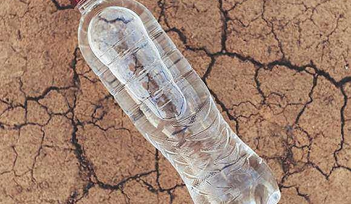 Consiglio di ricerca sul blog: bottiglia di plastica vuota su terreno secco e screpolato, simbolo di inquinamento ambientale e scarsità d'acqua.