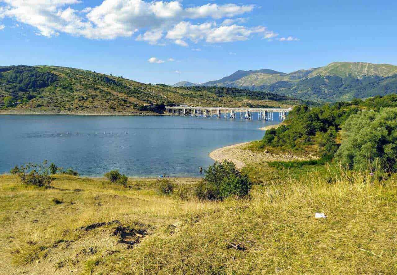 Lago tra le montagne con paesaggio naturale, area verde e cielo blu, centrale per l'energia idroelettrica in Italia.