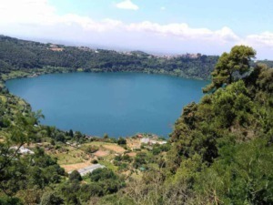 Laghetto circondato da verdi colline e vegetazione, vista panoramica su un paesaggio naturale rilassante e incontaminato.