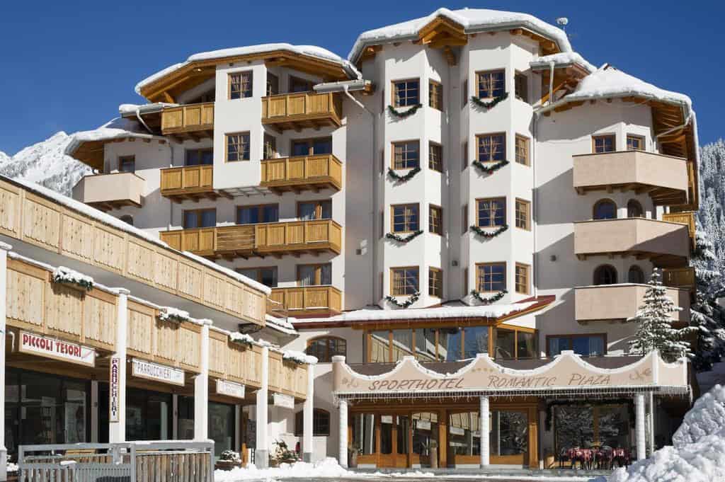 Dormire in un Hotel a Madonna di Campiglio tra neve perenne e laghi azzurri 3 Hotel in Madonna di Campiglio con architettura alpina, situato tra neve perenne e laghi cristallini, ideale per vacanze invernali. Struttura moderna con balconi in legno e servizi di qualità.
