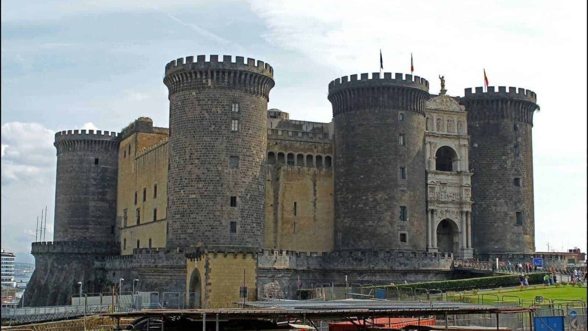 Forte di Castel Nuovo a Napoli, fortezza medievale con torri cilindriche e ingresso artistico, simbolo storico della città. Fotografia del castello con dettagli architettonici e il contesto urbano.
