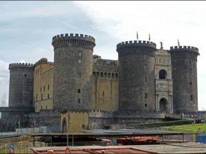 Forte di Castel Nuovo a Napoli, fortezza medievale con torri cilindriche e ingresso artistico, simbolo storico della città. Fotografia del castello con dettagli architettonici e il contesto urbano.