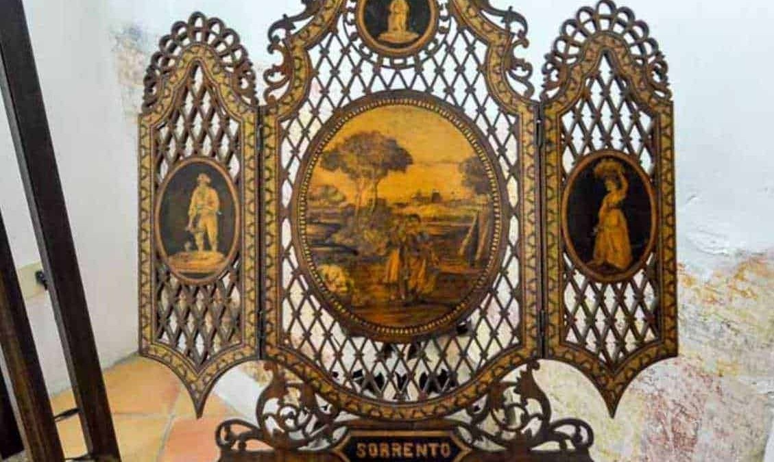 Antico schermo decorativo in legno intagliato con miniature dipinte a mano rappresentanti figure storiche e paesaggi, con la scritta "Sorrento" alla base, perfetto come oggetto di arredamento d'epoca.