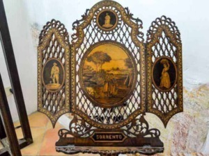 Antico schermo decorativo in legno intagliato con miniature dipinte a mano rappresentanti figure storiche e paesaggi, con la scritta "Sorrento" alla base, perfetto come oggetto di arredamento d'epoca.