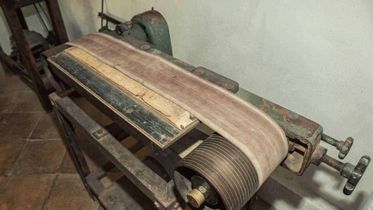 Lastra di metallo e carta su vecchio tornio industrial, strumenti di lavoro antichi, attrezzature meccaniche vintage, oggetti da collezione industriale, atmosfera retrò in ambiente di laboratorio o officina.