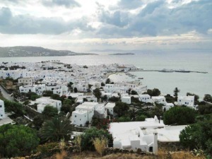 Pointer osteria di Mykonos, Grecia, vista panoramica delle case bianche, edificio in stile tradizionale, mare cristallino, cielo nuvoloso, attività turistica, località costiera.