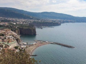 Spiaggia di Amalfi con porticciolo e scogliera panoramica, vista sulla costa amalfitana e il mare cristallino del Mar Tirreno. Paesaggio costiero caratteristico, ideale per vacanze in Italia.