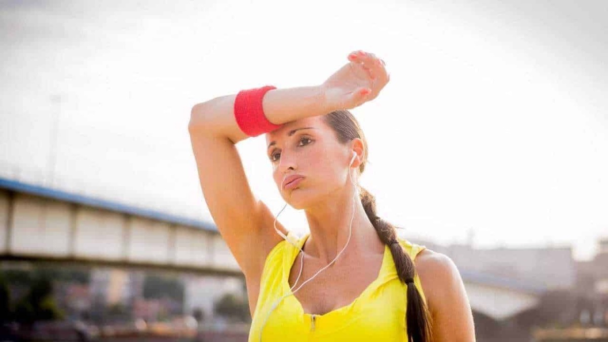 Sudore donna in allenamento durante corsa all'aperto con cuffie, sport e fitness.