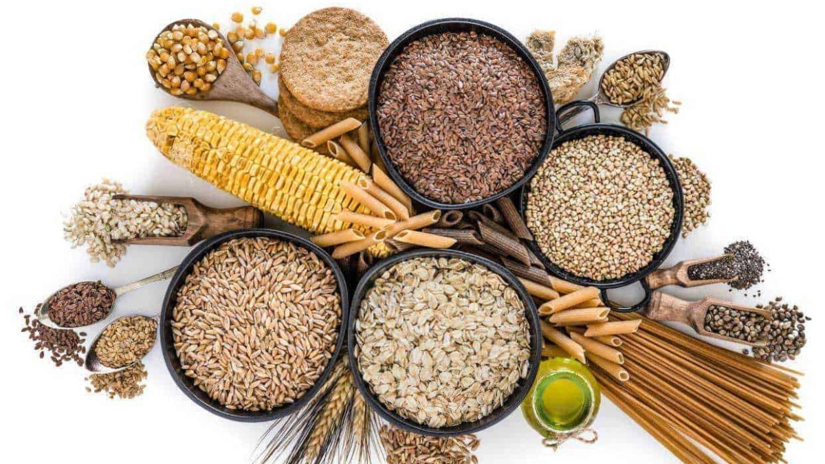 Azienda alimentare con varietà di cereali, pasta e semi in ciotole di legno, olio d'oliva e pasta secca, scena colorata e ricca di alimenti salutari.