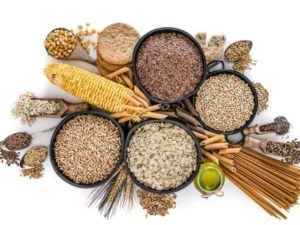 Azienda alimentare con varietà di cereali, pasta e semi in ciotole di legno, olio d'oliva e pasta secca, scena colorata e ricca di alimenti salutari.