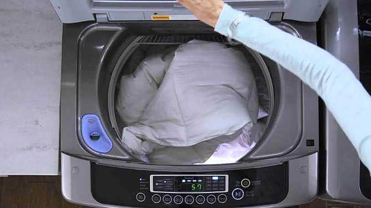 Pulire la lavatrice carica dall'alto: Lavatrice che effettua il ciclo di lavaggio con carico di biancheria, primo piano dettaglio del contenitore aperto.