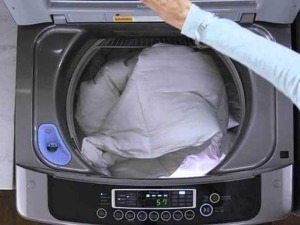 Pulire la lavatrice carica dall'alto: Lavatrice che effettua il ciclo di lavaggio con carico di biancheria, primo piano dettaglio del contenitore aperto.