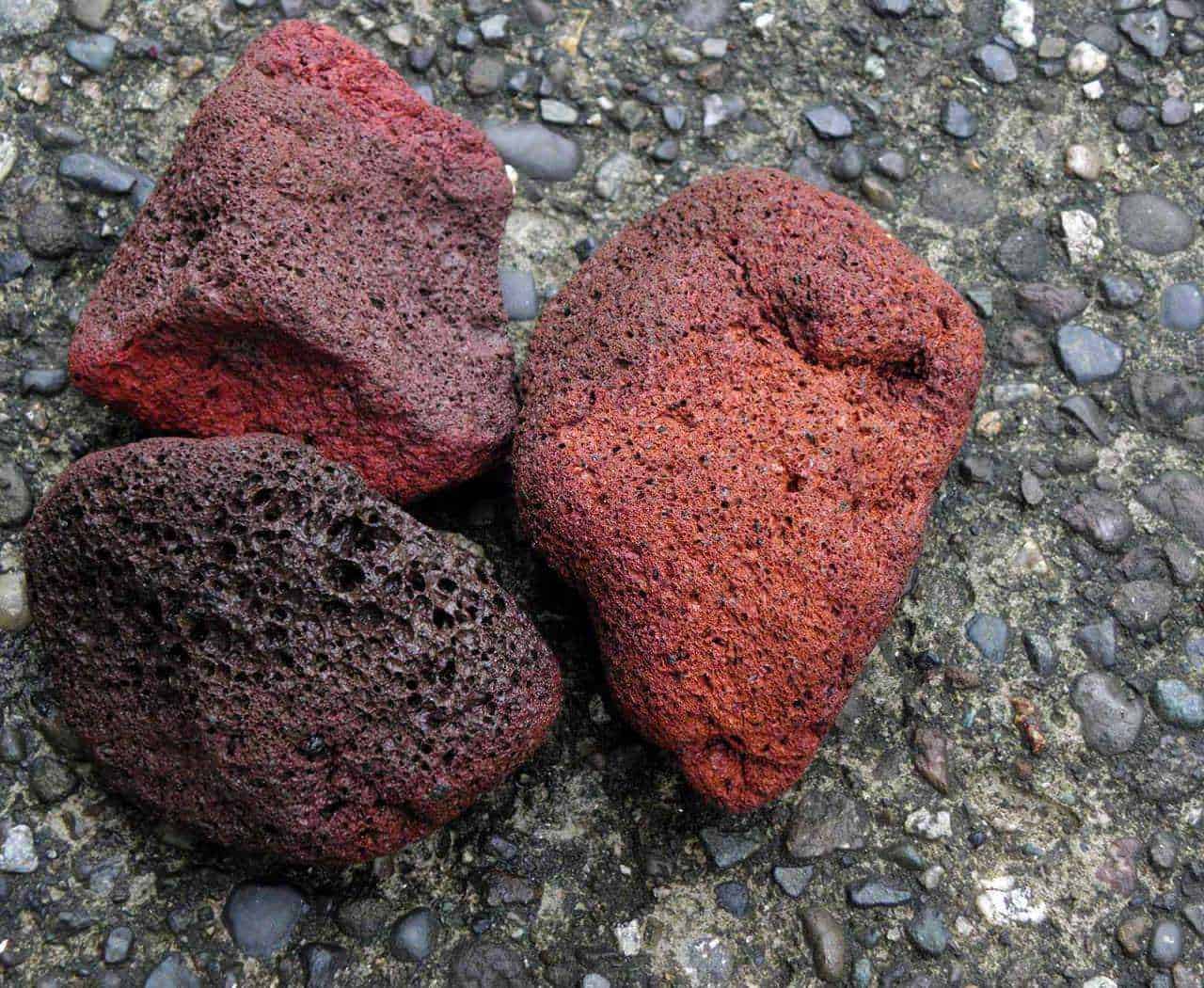 Pietra pomice per i piedi: Pietra pomice piedi. Quale scegliere tra naturale e sintetica? pietre laviche rosse e nere sulla strada gravellata.