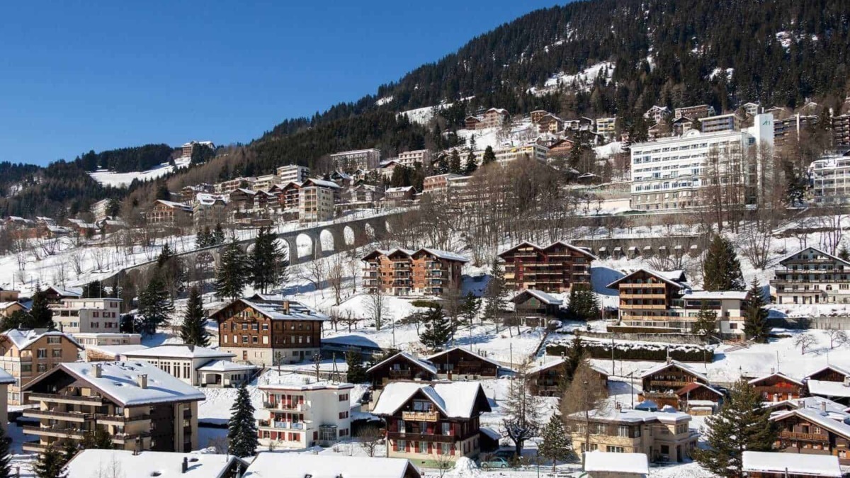 Neve su case e appartamenti di montagna nel paesaggio alpino in inverno.