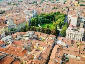 Vedere aerea di un parco urbano circondato da edifici storici e moderni nel centro di una città italiana, con strade e tetti in terracotta tipici.